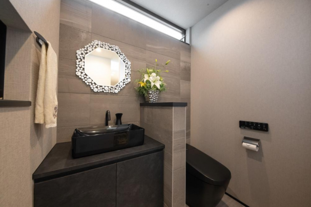 【参考プラン例/トイレ】ブラックとグレーで統一された高級感のあるトイレスペース。タンクレストイレで空間をすっきりと見せ、手洗い・カウンターをブラックで統一。壁面には脱臭効果のあるエコカラット（ストーングレース）。